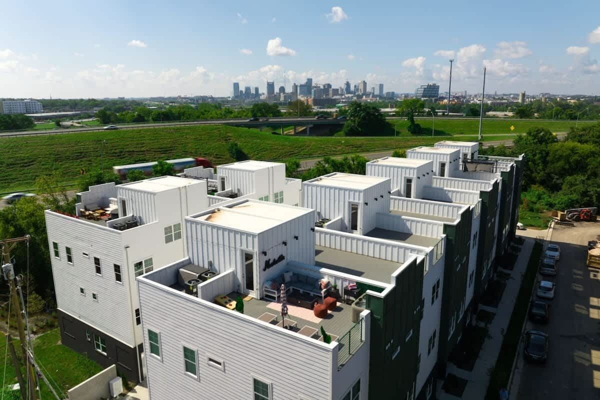 A modern multi-story building with a rooftop terrace and a parking area.