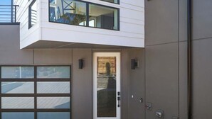 A modern two-story building with a garage door, a small entrance with a door, and a mailbox. - Perch - View Ridge Guest Suite: Cozy 1BR ADU Retreat (Seattle)