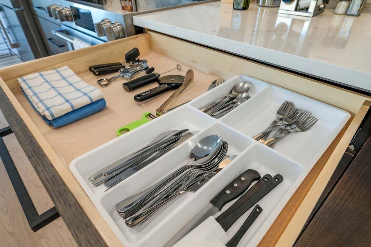 Eine Schublade mit ordentlich verstauten Küchenutensilien, darunter Gabeln, Löffel, Messer und ein Pfannenwender.
