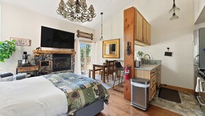 A cozy room with a bed, a TV, a fireplace, a dining area, and a kitchenette. - TahoeCozy Woodland Retreat • Pool • Hot Tub • Beach (Tahoe Vista)