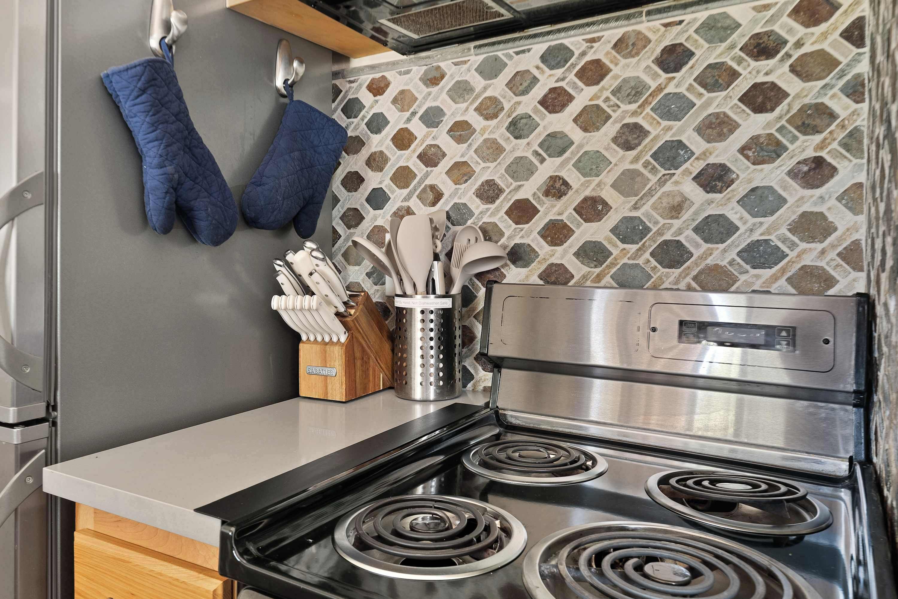 A kitchen with a stove, oven, and a utensil holder.