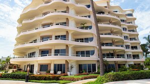 A multi-story hotel with balconies, a landscaped garden, and palm trees. - Gorgeous Two-Story Penthouse Private Community on the Beach! (Flamingos)