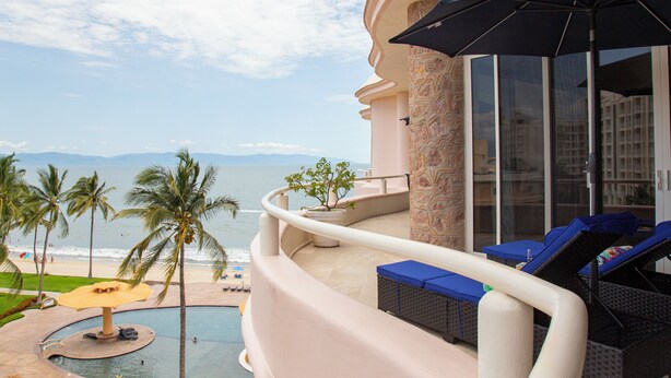 A balcony with a pool, lounge chairs, and a view of the beach and ocean. - Gorgeous Two-Story Penthouse Private Community on the Beach! (Flamingos)