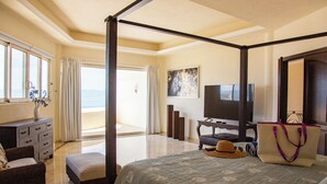 A four-poster bed with a view of the beach, a television, and a desk with a chair. - Gorgeous Two-Story Penthouse Private Community on the Beach! (Flamingos)