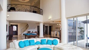 A spacious living area with a white sectional sofa, a pool table, and a balcony with a railing. - Gorgeous Two-Story Penthouse Private Community on the Beach! (Flamingos)