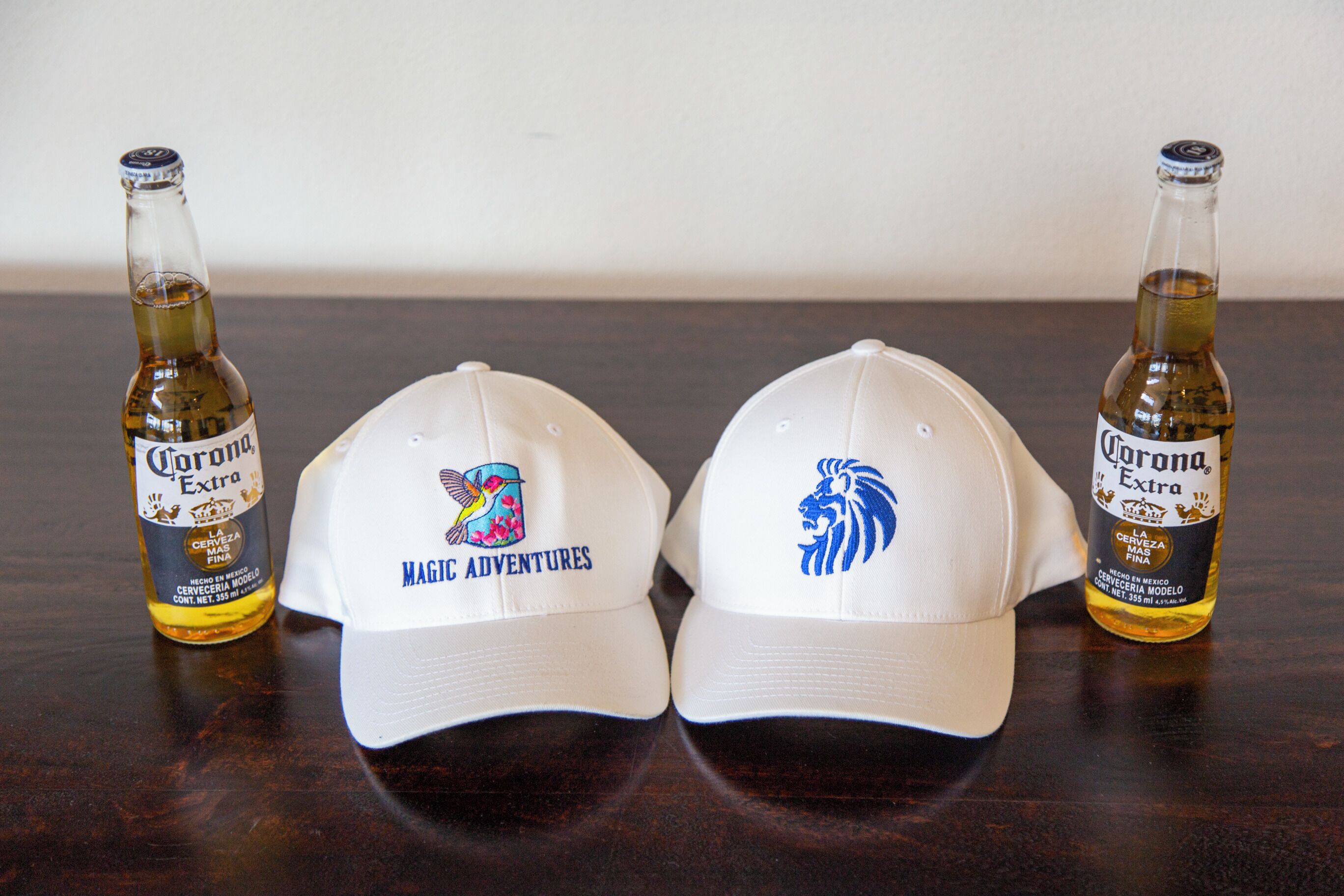 Zwei Flaschen Corona Extra Bier und zwei weiße Baseballkappen mit Logos.