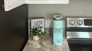 Una cucina con un armadietto bianco, un forno in acciaio inox, una macchina da caffè Keurig e un cartello con su scritto 'Ti amo fino al ponte'.