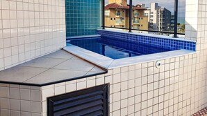 Une piscine sur le toit, avec des murs recouverts de carreaux et une vue sur les bâtiments environnants.
