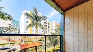 Un balcon donnant sur un quartier résidentiel, avec vue sur des immeubles et une voiture garée.