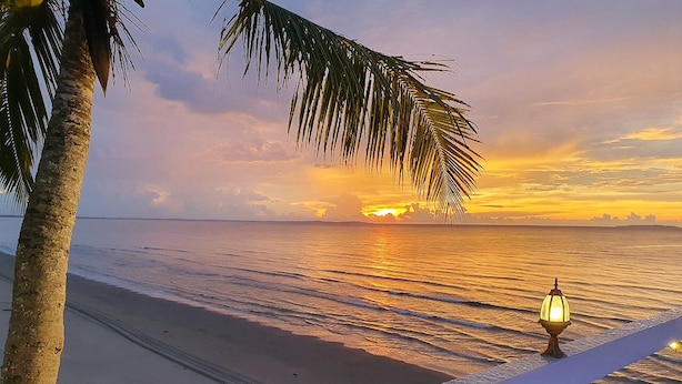 A beach view with a palm tree and a lamp post.
