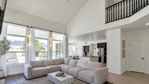 A spacious living room with a large sectional sofa, a marble coffee table, and a view of the backyard through large windows. - Private Heated Pool, Putting Green, Pool Table, BBQ, WIFI, Near Golf, Dining & Mayo Clinic+FREE GOLF (Scottsdale)
