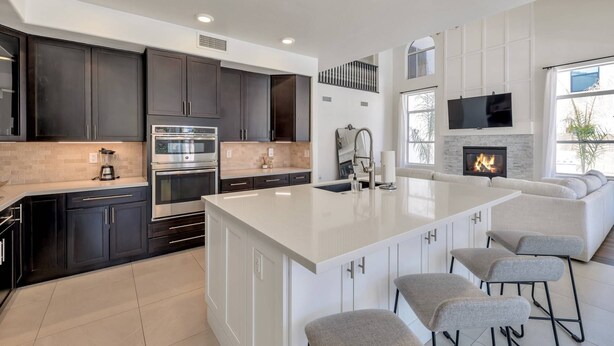 A modern kitchen with dark cabinets, stainless steel appliances, and a large island with bar stools. - Private Heated Pool, Putting Green, Pool Table, BBQ, WIFI, Near Golf, Dining & Mayo Clinic+FREE GOLF (Scottsdale)