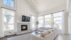 A spacious living room with a fireplace, large windows, and a modern sofa. - Private Heated Pool, Putting Green, Pool Table, BBQ, WIFI, Near Golf, Dining & Mayo Clinic+FREE GOLF (Scottsdale)