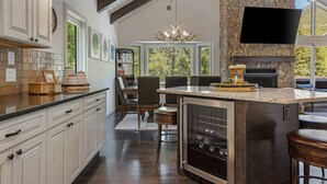 A spacious kitchen with a large island, stone accent wall, and a built-in wine cooler. - Large West Vail Home - Hot Tub & Ski Lockers (Vail)