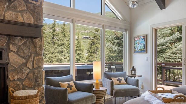 A cozy living room with stone walls, large windows, and comfortable seating. - Large West Vail Home - Hot Tub & Ski Lockers (Vail)