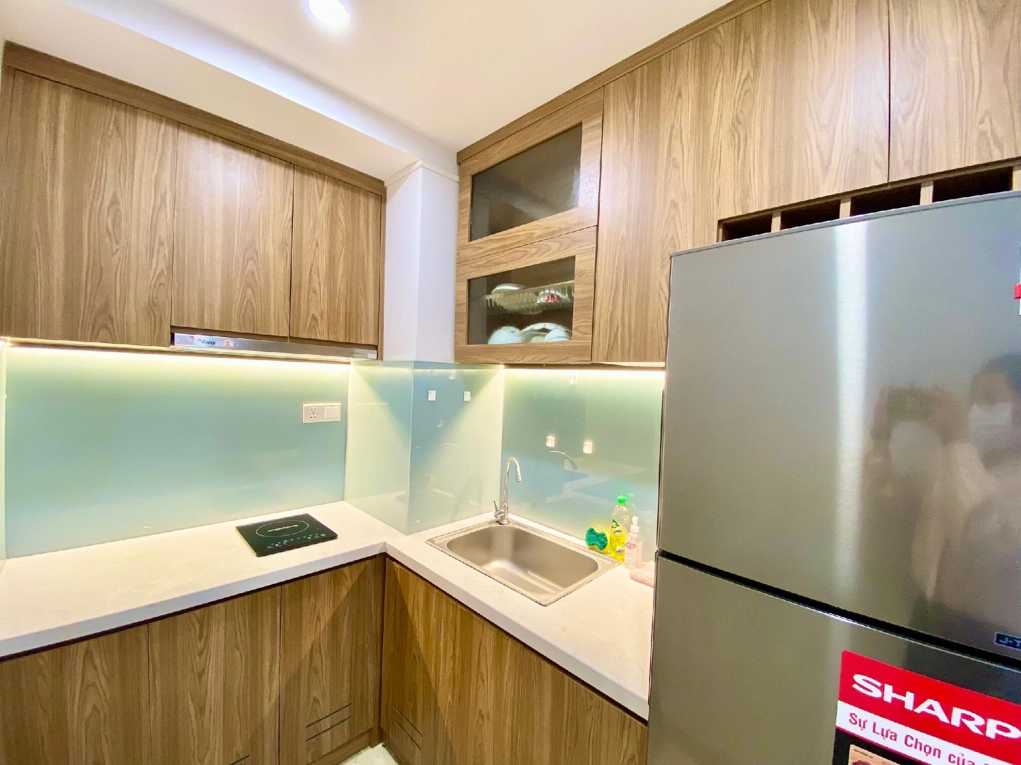 A modern kitchen with wooden cabinets, a stainless steel refrigerator, and a built-in sink.