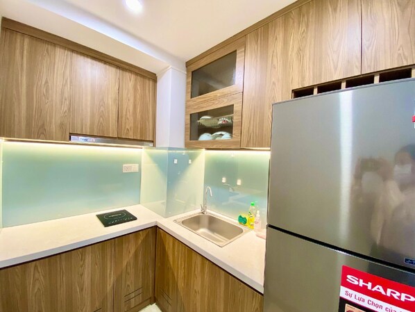 A modern kitchen with wooden cabinets, a stainless steel refrigerator, and a built-in sink.