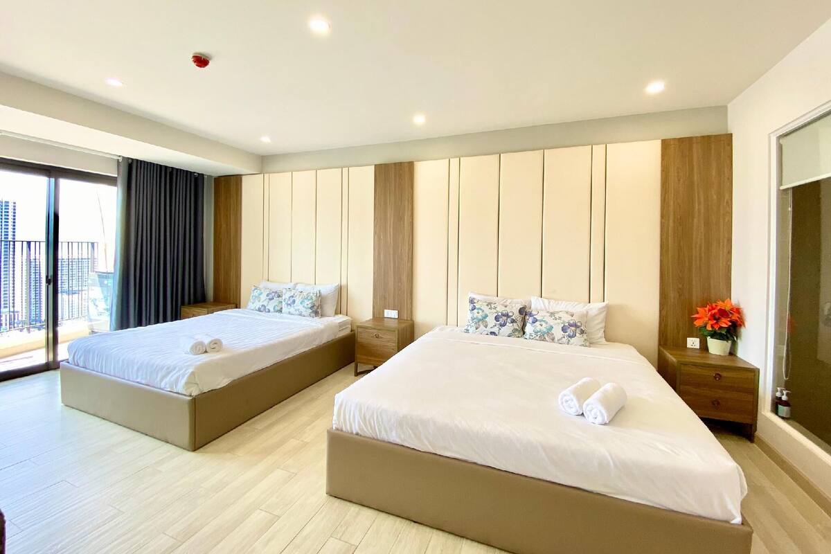 Ein modernes Hotelzimmer mit zwei Betten, einem großen Fenster und Blick auf die Stadt.