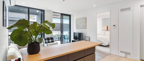A modern kitchen with a wooden countertop, a potted plant, and a dining area with a table and chairs.