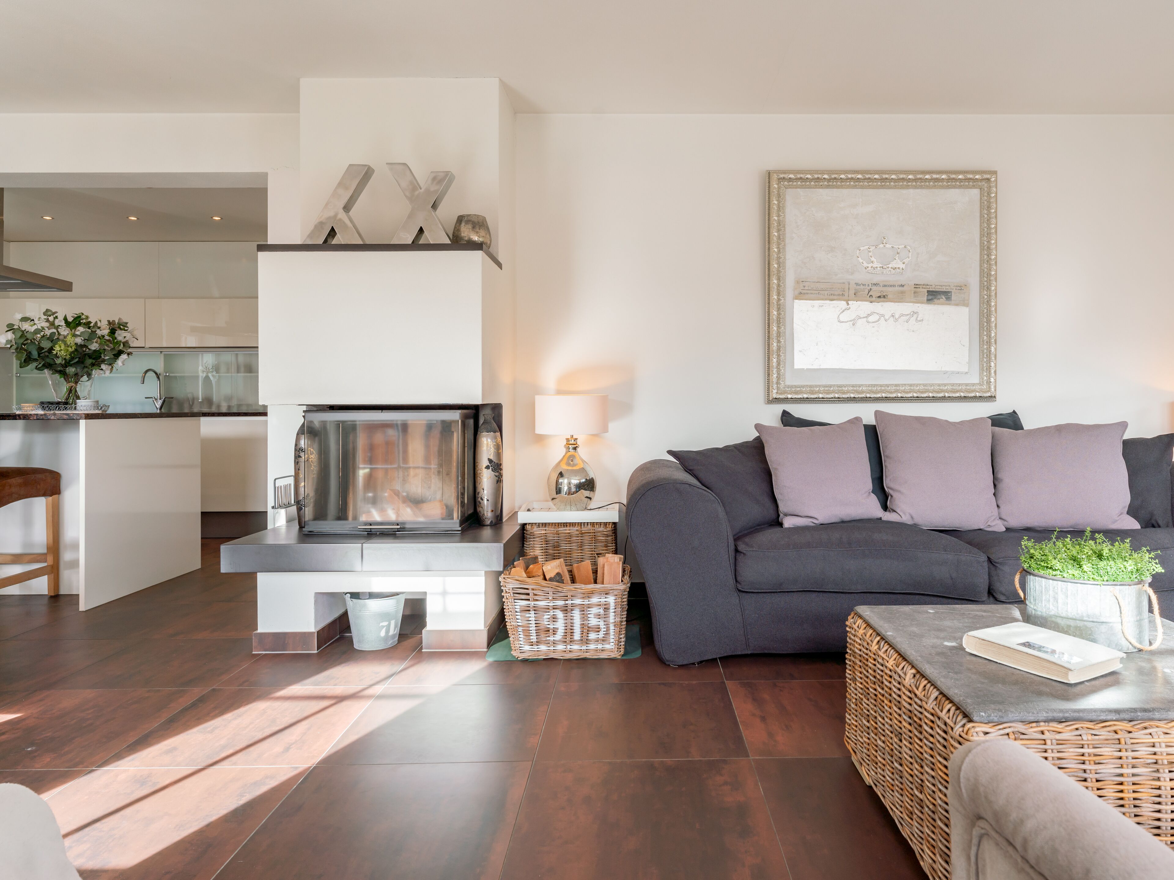 Una sala de estar moderna con chimenea, un sofá gris y una mesa de centro de mimbre.