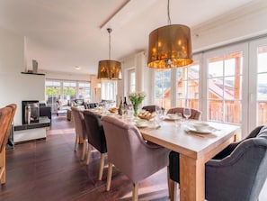 A dining area with a wooden table, chairs, and hanging pendant lights.