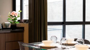 Un comedor con una mesa dispuesta para cuatro personas, un florero con flores y vistas amplias a través de grandes ventanales.