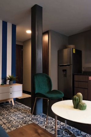 Cozy living space with a patterned accent wall, green chair, and small table.