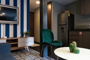 Relax in a compact living space with a flat-screen TV, kitchenette, and comfortable seating area.