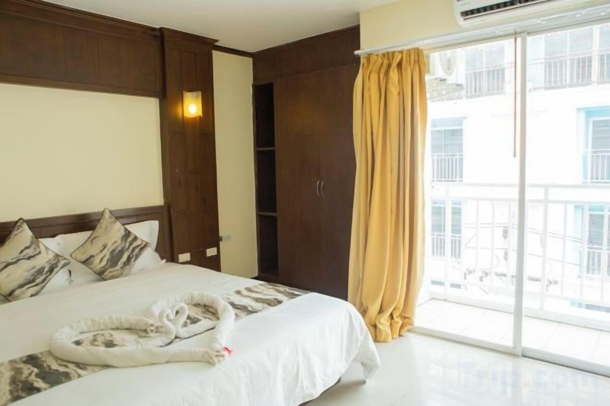 Ein Hotelzimmer mit einem Bett, einem Kleiderschrank, einer Schiebetür zum Außenbereich und einem Fenster mit Vorhängen.