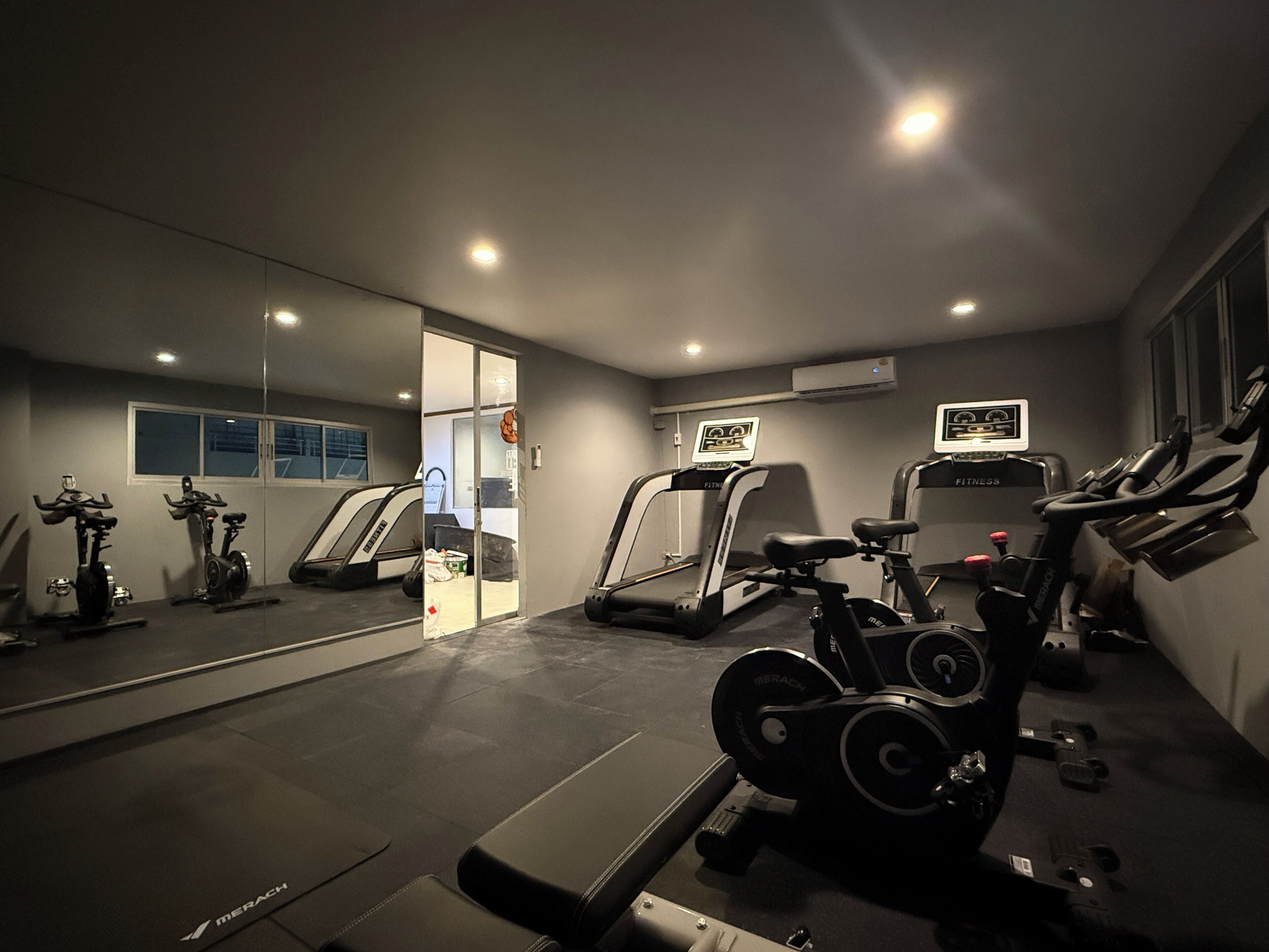 A gym with exercise equipment, a treadmill, and a mirrored wall.