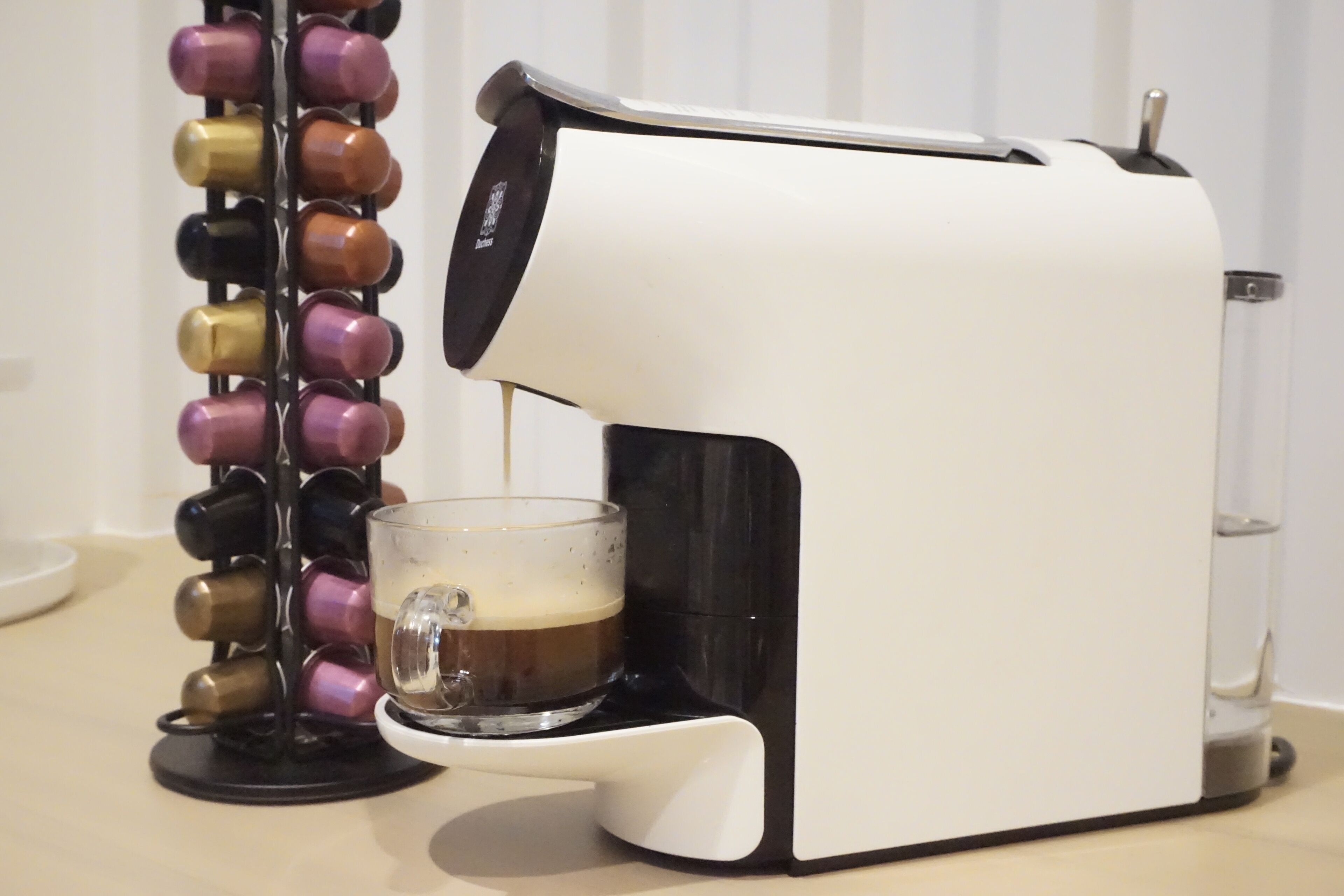 A coffee machine dispensing coffee into a glass cup.