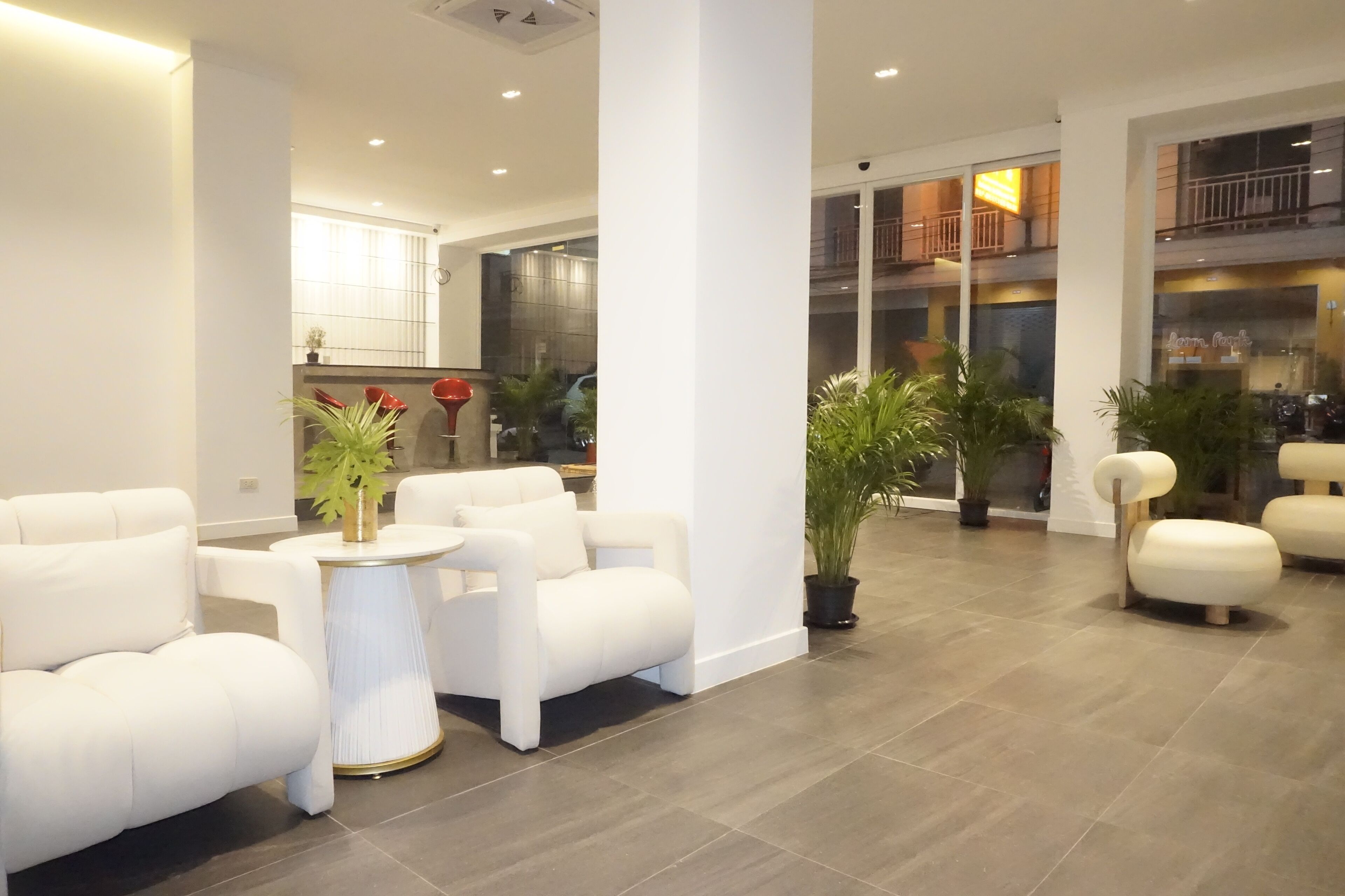 A modern living room with white sofas, a round coffee table, and potted plants.