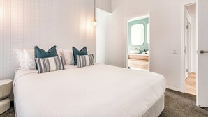 Ein Schlafzimmer mit einem großen Bett, weißen Wänden und einer Tür zu einem Badezimmer.