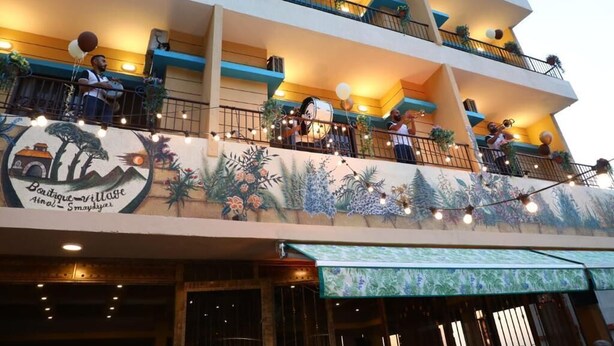 A multi-story hotel with balconies, string lights, and a mural. - Village Boutique Hotel (Khenchara)
