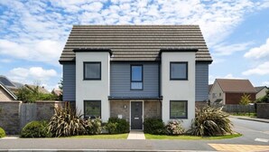 A two-story residential building with a grey facade, a dark roof, and a central entrance. - Modern Home with Parking, nr Saunton Sands (Barnstaple)