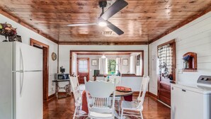 A kitchen with a dining area, wooden ceiling, and a ceiling fan.