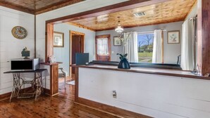 A cozy room with wooden floors, a wooden ceiling, a desk with a computer, a chair, and a window with a view of the outdoors.