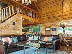 Interno di una baita in legno con angolo soggiorno, scala e cucina.