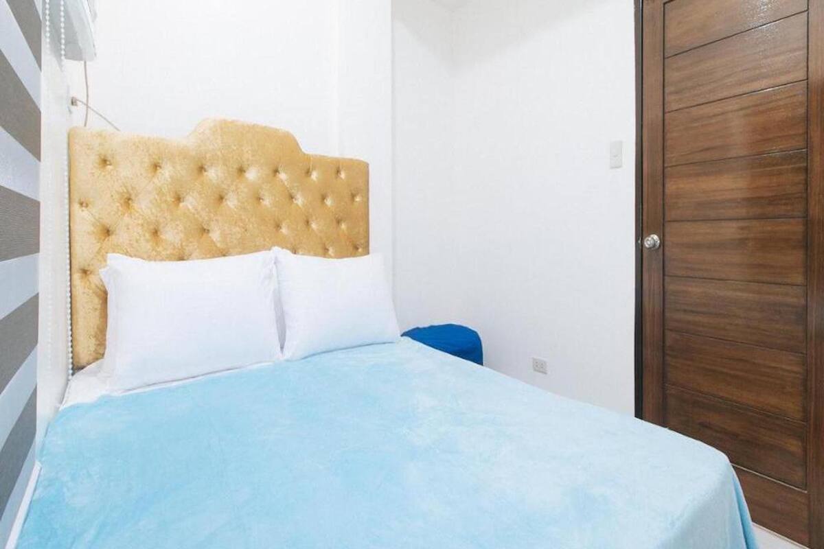 A bed with a tufted headboard, a blue bedspread, and white pillows.