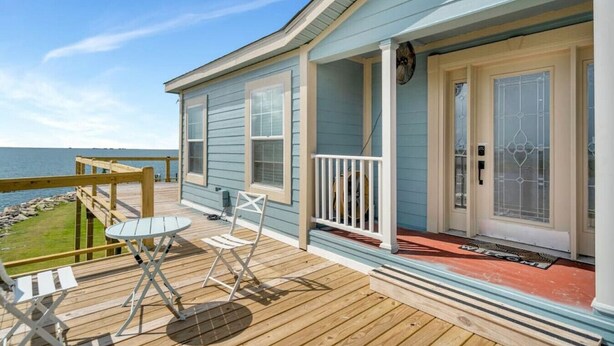 A coastal house with a deck, a small table, and two chairs. - Family Friendly Waterfront Home | Private backyard (New Orleans)