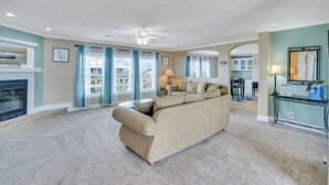 A living room with a beige sofa, a fireplace, and a dining area visible through a glass door. - Family Friendly Waterfront Home | Private backyard (New Orleans)