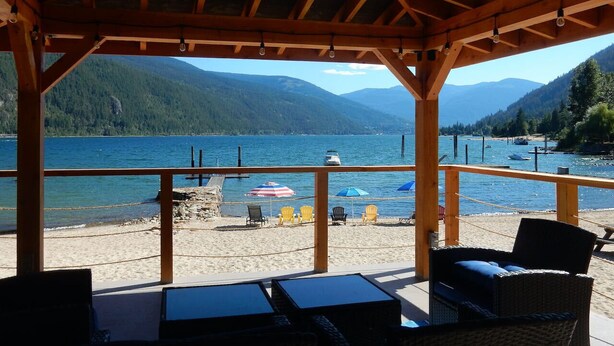 A covered outdoor seating area with a view of a lake and mountains. - Beautiful Beach front cottage near Nelson, BC (Nelson)