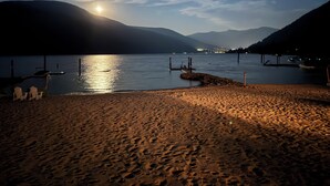 A beach with a calm lake, boats, and a dock. - Beautiful Beach front cottage near Nelson, BC (Nelson)