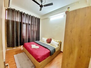 Cozy retreat with a single bed, wooden wardrobe, and ceiling fan.