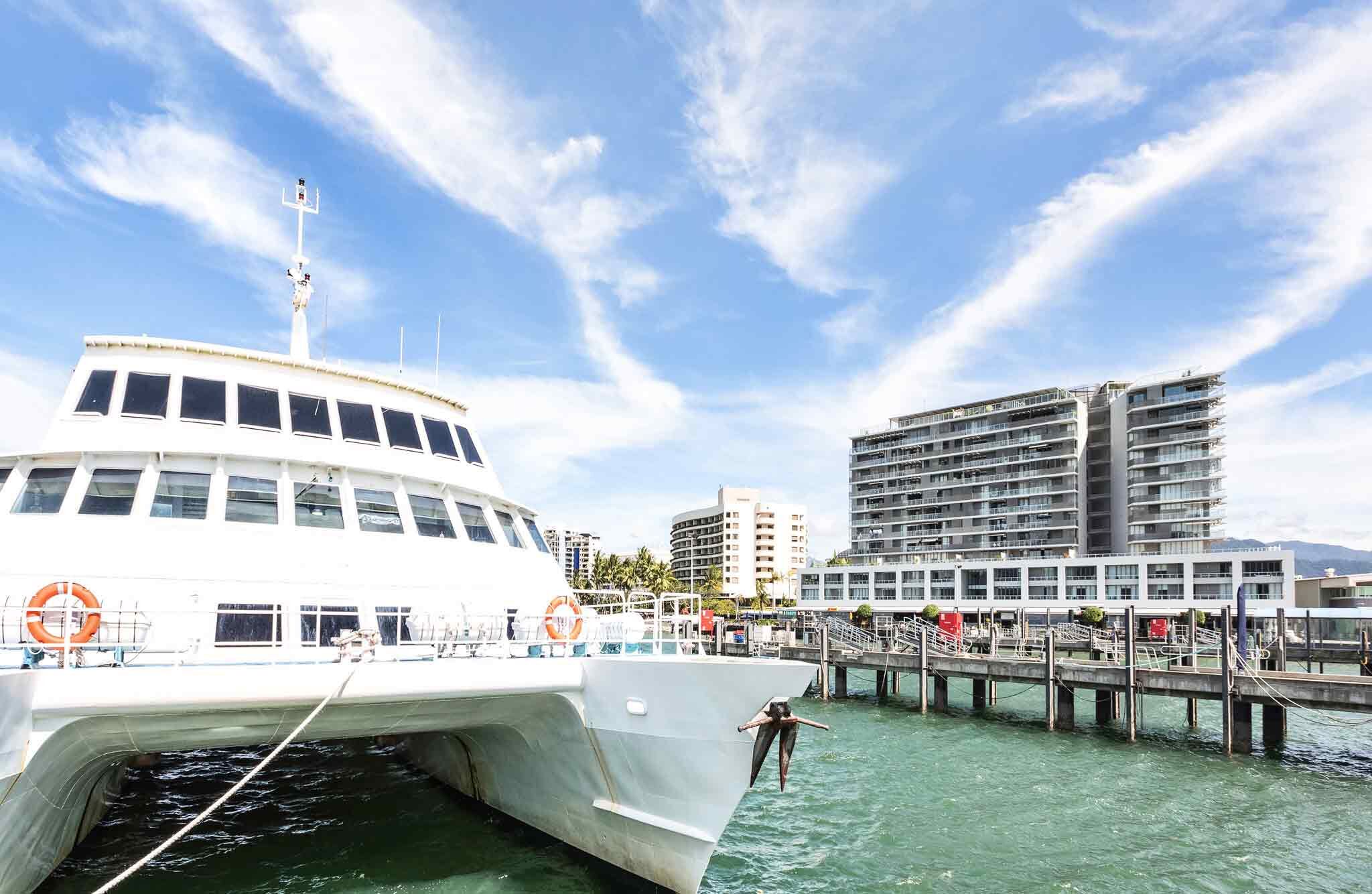 A white boat docked at a pier with a cityscape in the background.
