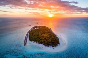 An aerial view of a tropical island with a clear sky and sunset.