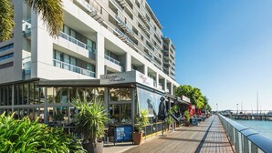 Un hôtel moderne à plusieurs étages, doté d’une terrasse et offrant une vue sur le bord de l’eau.
