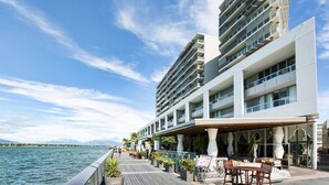 Un hôtel situé au bord de l’eau, doté de nombreux balcons, d’un espace extérieur aménagé et offrant une vue sur l’eau.