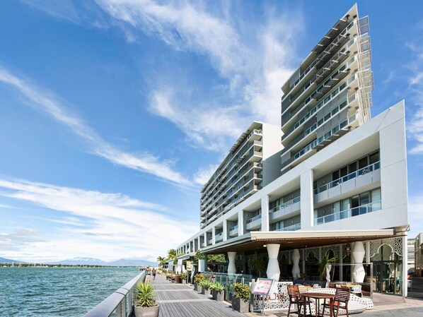 A waterfront hotel with multiple balconies, outdoor seating, and a view of the water.