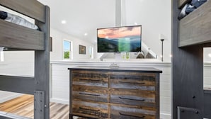 Een moderne kamer met stapelbedden, een houten dressoir, een flatscreen televisie en uitzicht op de omgeving.